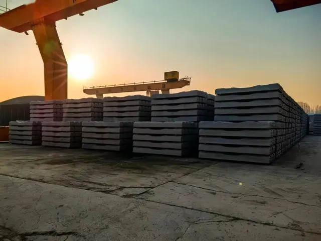 Concrete railway sleepers stacked in a stockyard at sunset